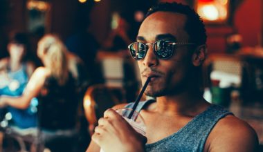 man sipping his drink wearing sunglasses