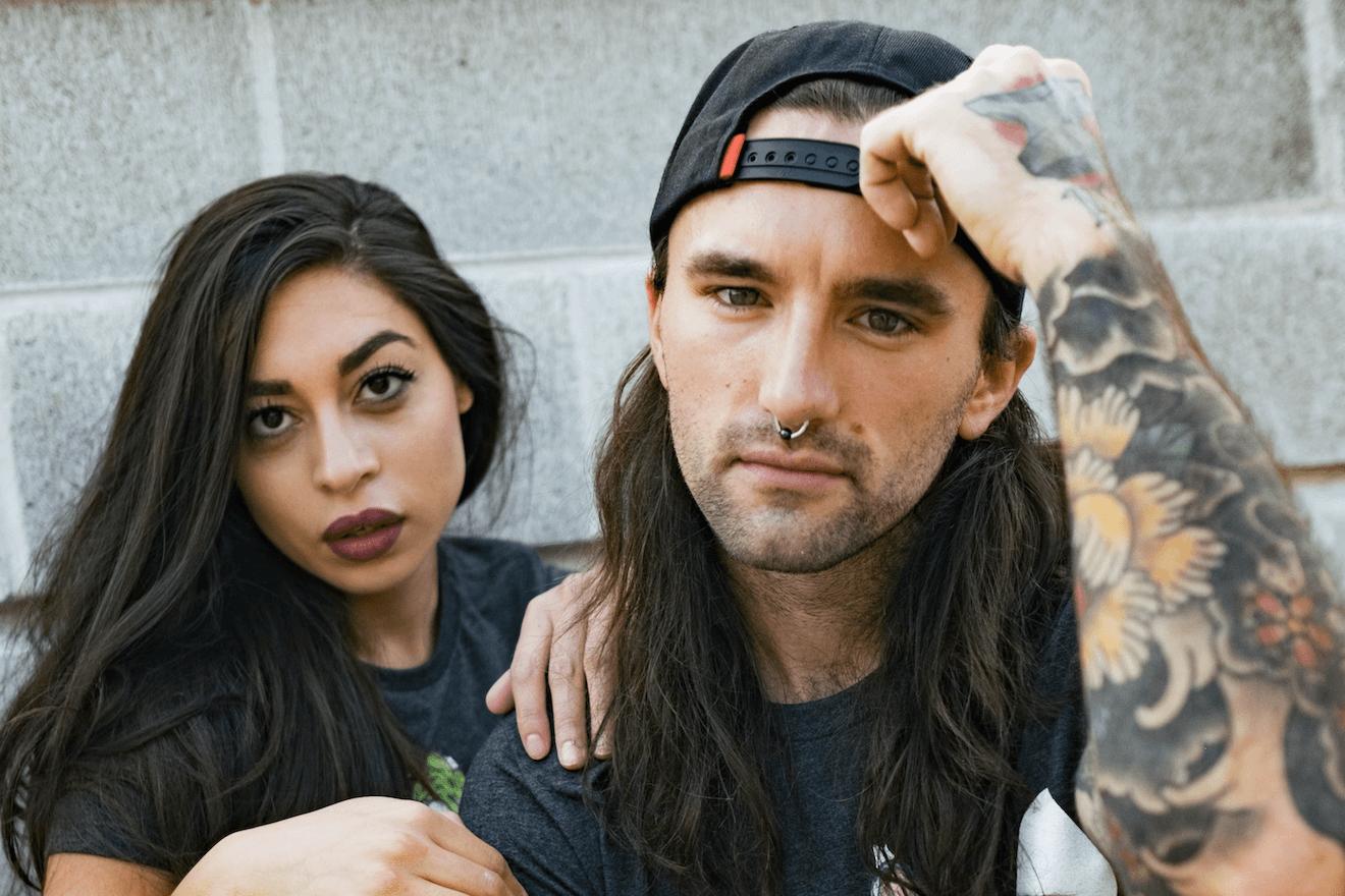 Couple with tattoos by cinder block wall